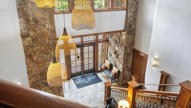 A stone-floored interior with hanging lamps, a wooden bench, and a staircase. - Timbers & Lone Eagle by Vail Resorts (Keystone)