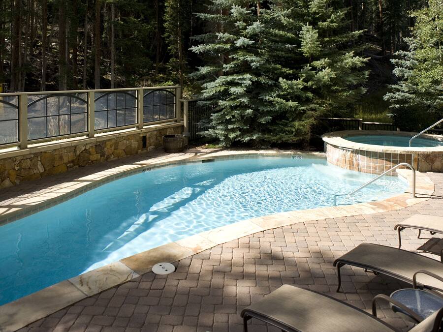 Une piscine bordée de pierres, un jacuzzi et des chaises longues.