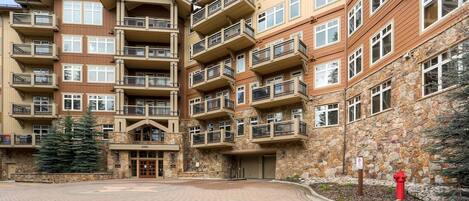 A multi-story hotel with balconies, stone facade, and a paved courtyard.