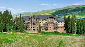 A multi-story hotel with a stone facade, multiple balconies, and a view of a mountainous landscape. - Timbers & Lone Eagle by Vail Resorts (Keystone)