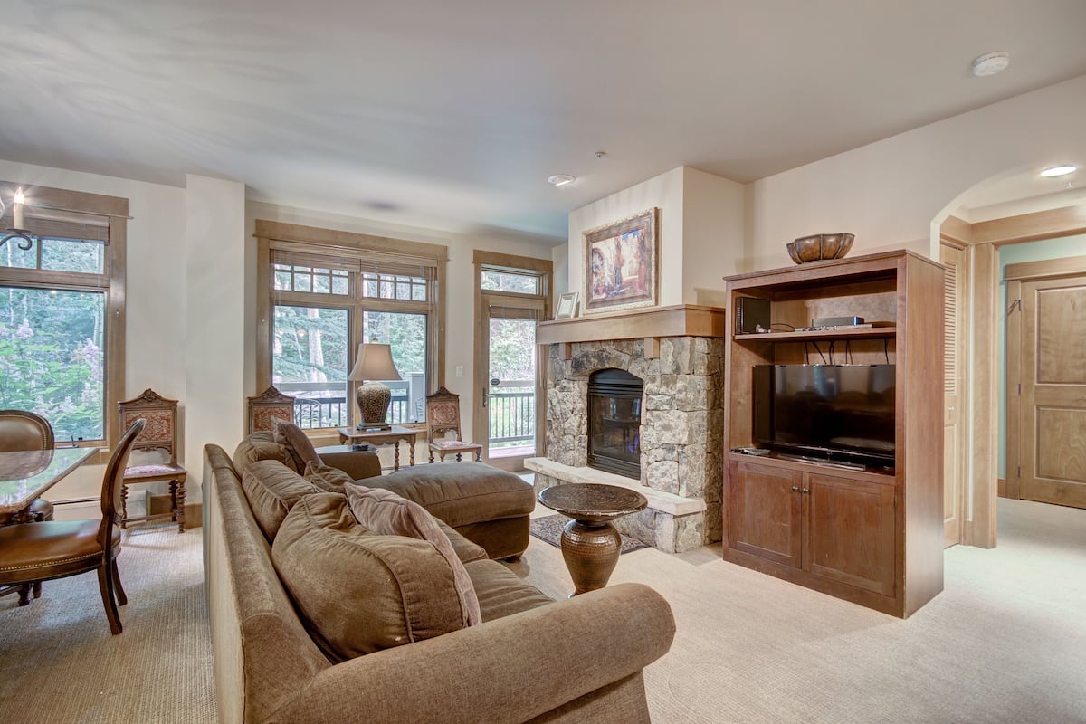 A spacious living room with a stone fireplace, a large flat-screen TV, and a comfortable seating area.