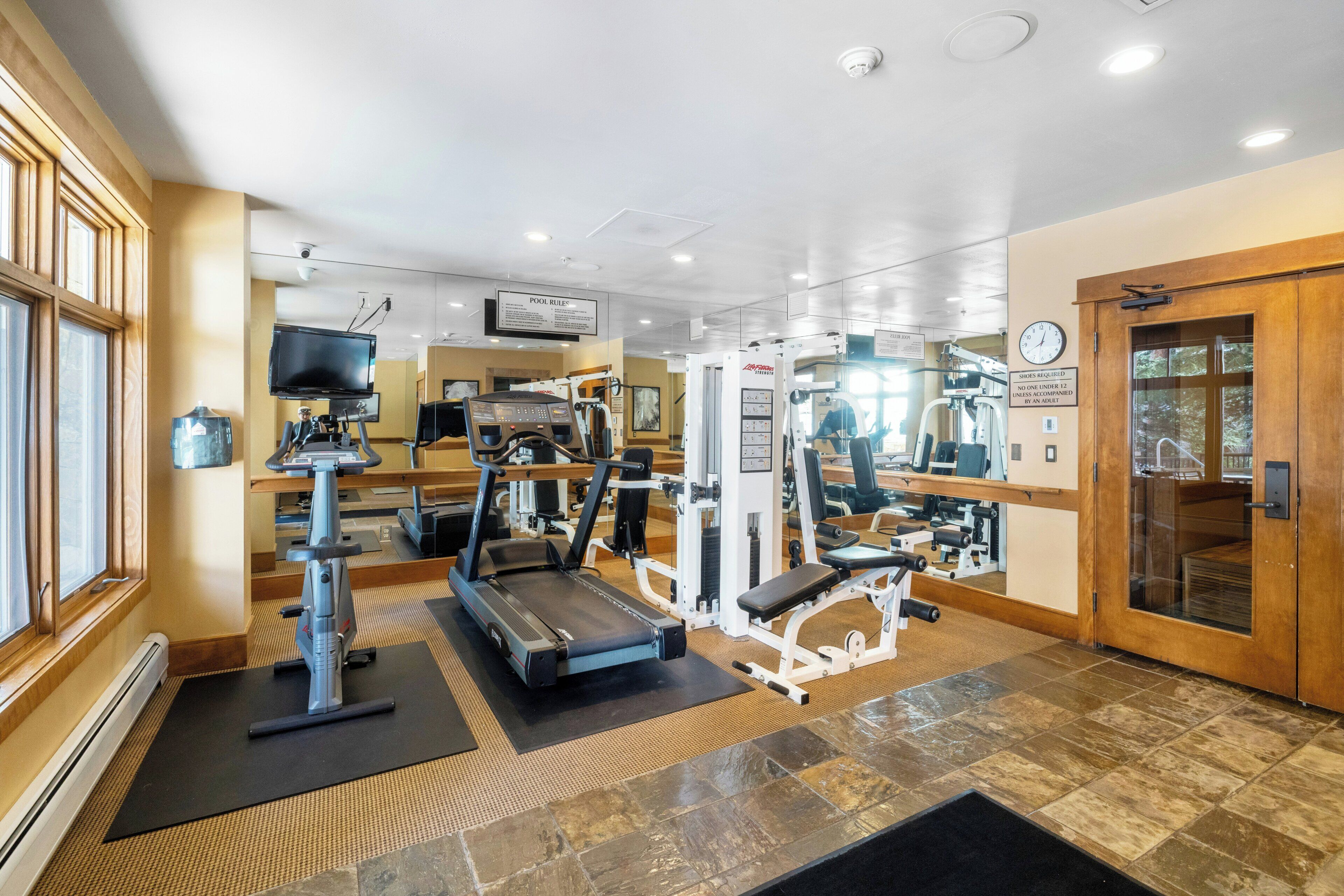 Un gimnasio con cintas de correr, máquinas de pesas y un espejo.