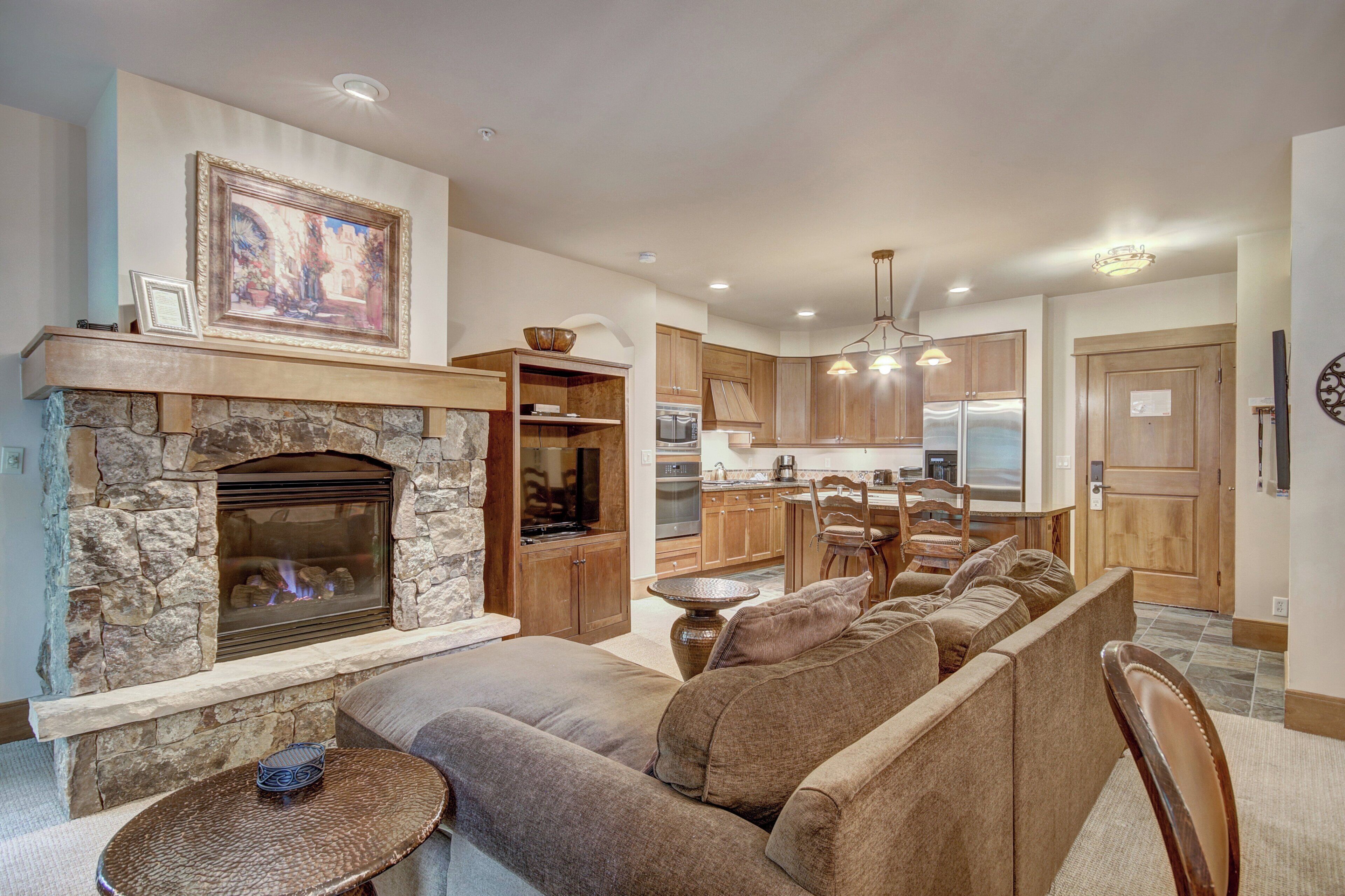 A modern living room with a stone fireplace, a sofa, and a dining area.