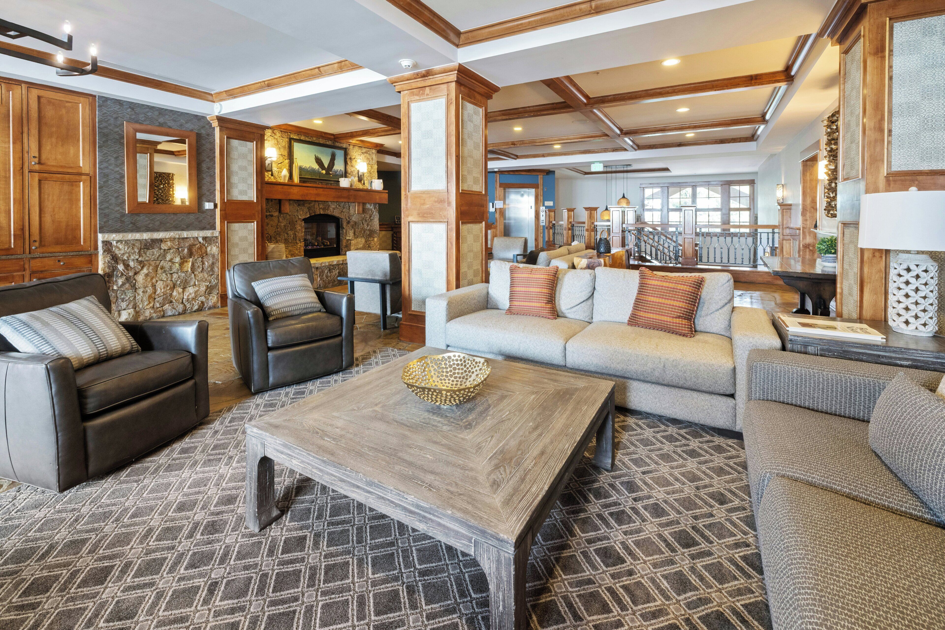 A spacious living area with a fireplace, leather sofas, a coffee table, and a patterned rug.