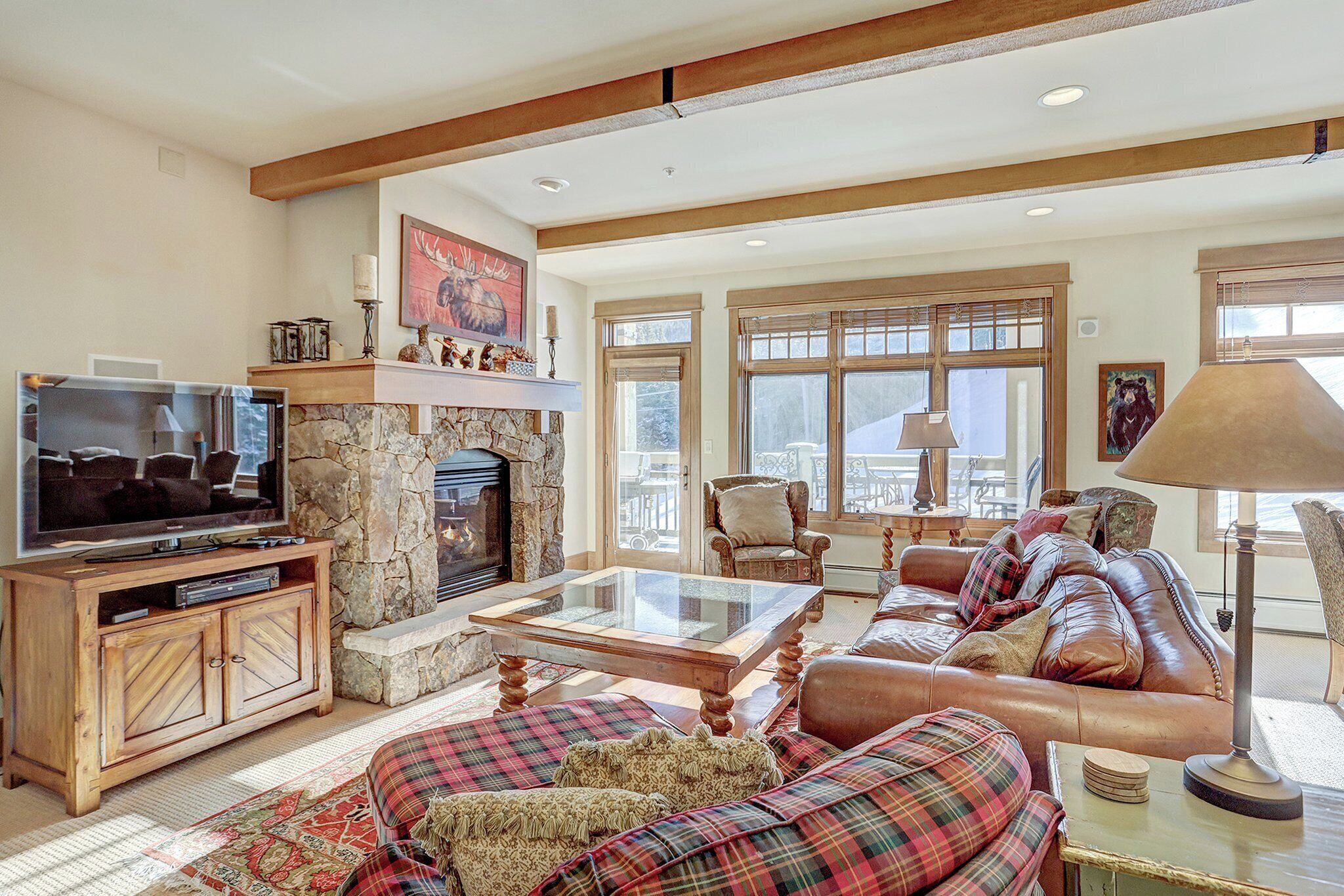 A cozy living room with a stone fireplace, leather sofa, and a television on a wooden cabinet.