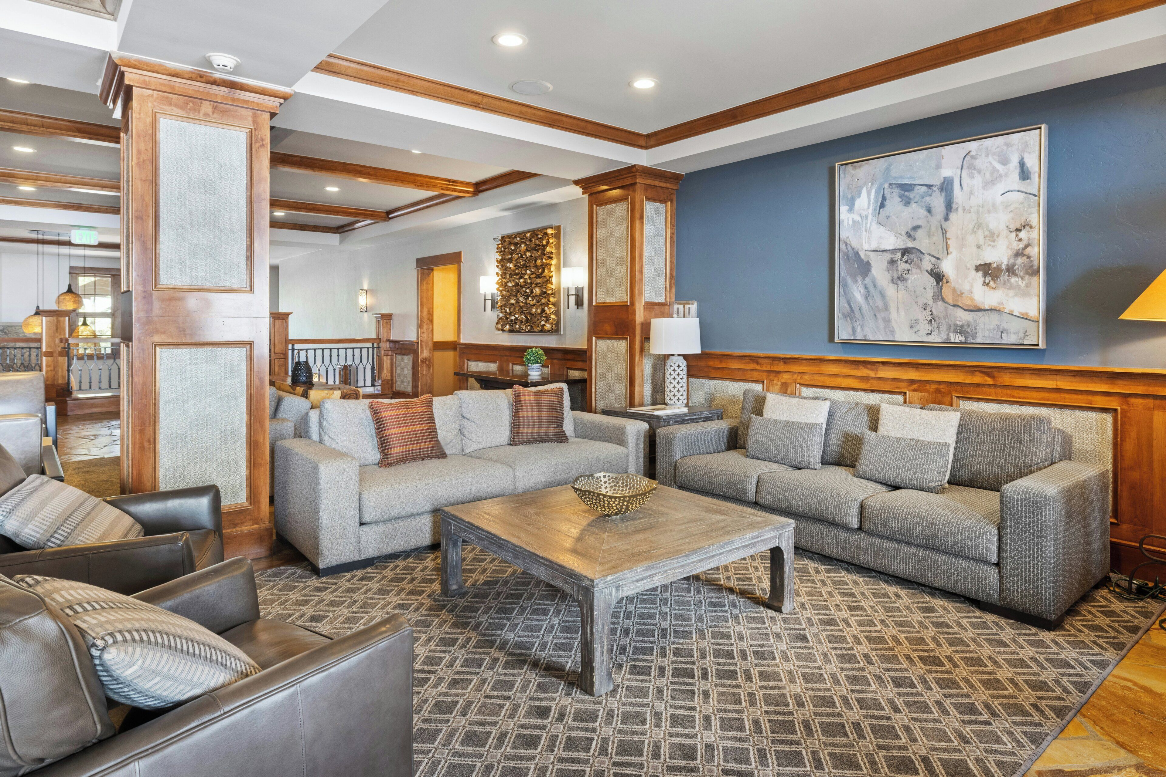 A spacious living area with two grey sofas, a wooden coffee table, and a patterned rug.