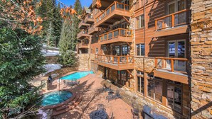 A multi-story lodge with balconies, a swimming pool, and a patio area with outdoor seating. - Timbers & Lone Eagle by Vail Resorts (Keystone)