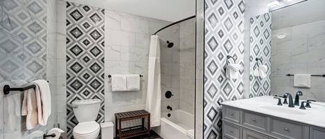 A bathroom with a toilet, shower, and vanity with a mirror.