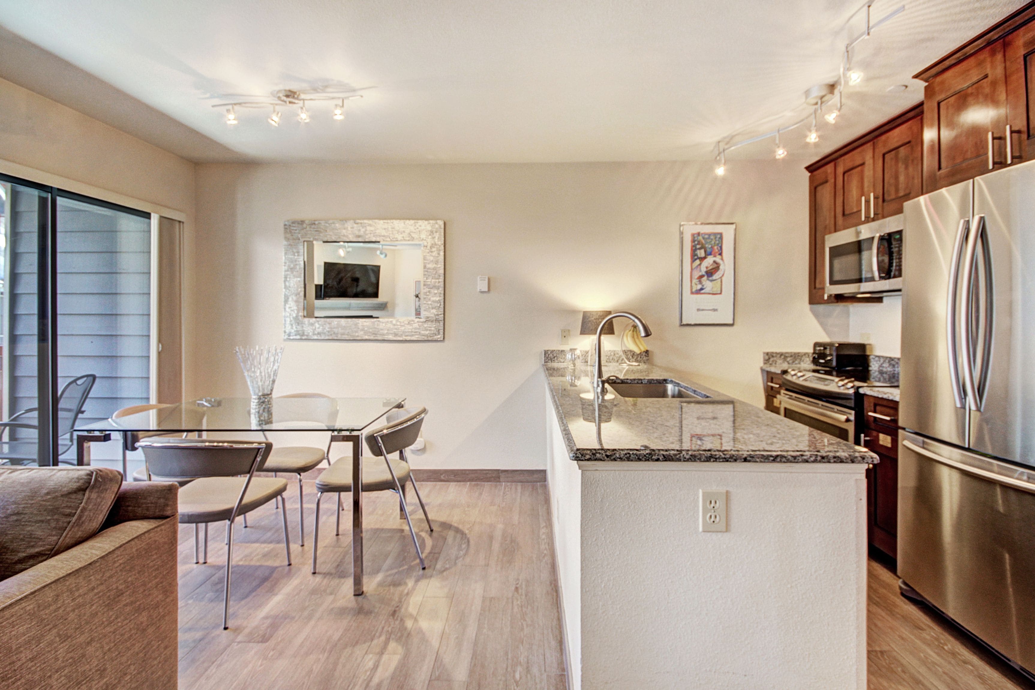 A modern kitchen with a central island, stainless steel appliances, and a dining area with bar stools.