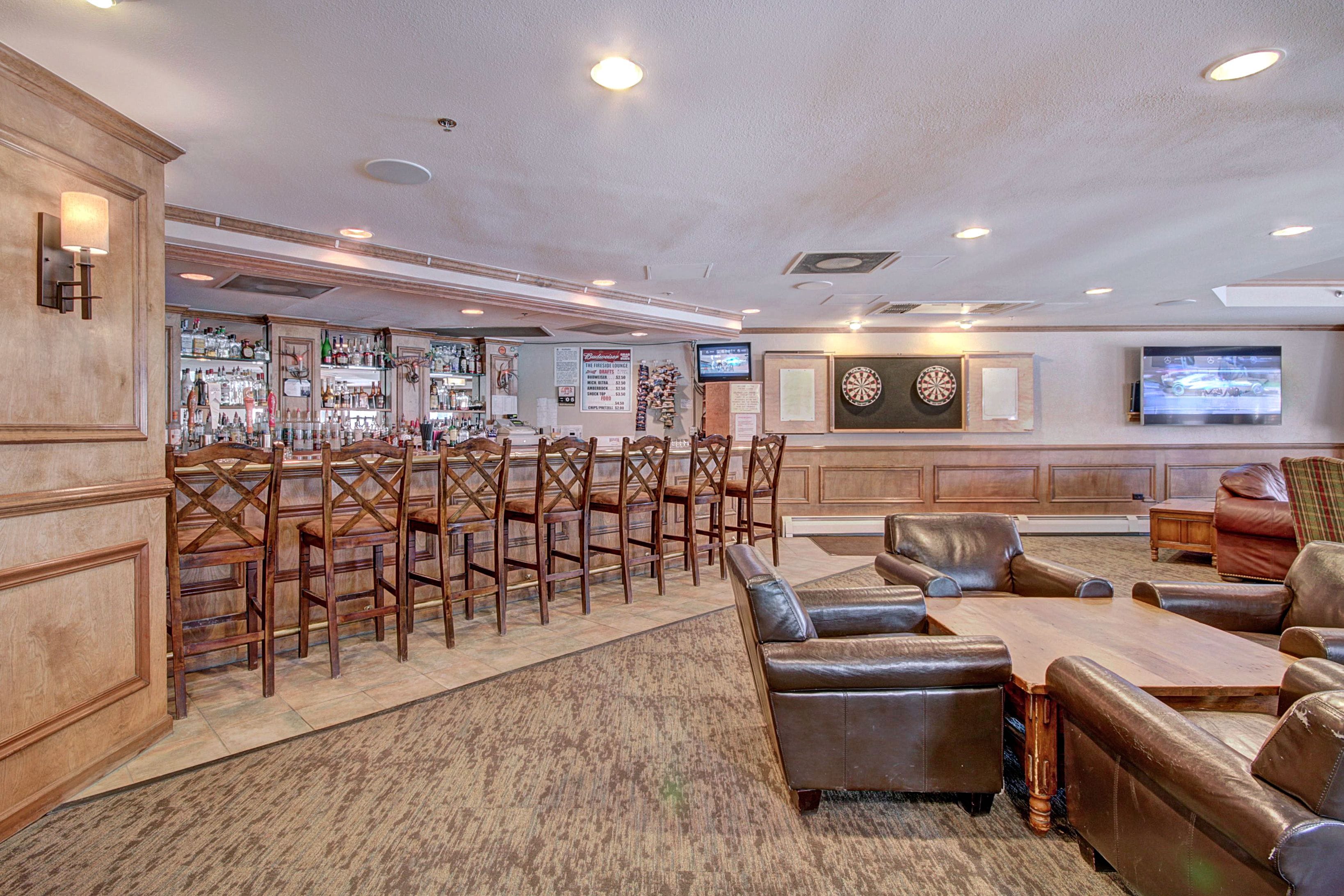 A bar area with wooden chairs, a bar counter, and a television screen.