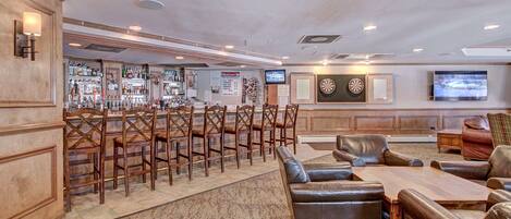 A bar area with wooden chairs, a bar counter, and a television screen.