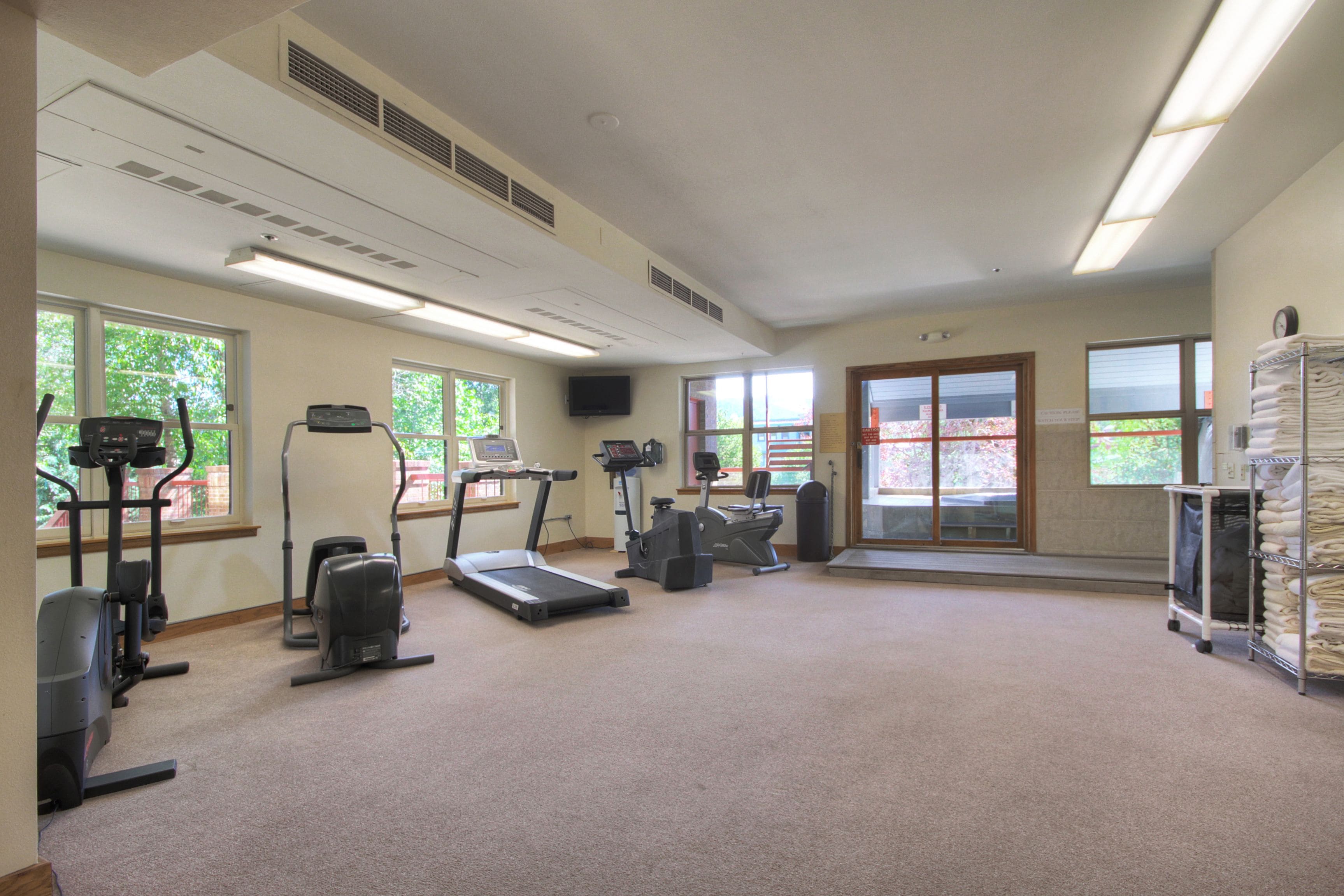 A gym with treadmills, elliptical machines, and a stationary bike.