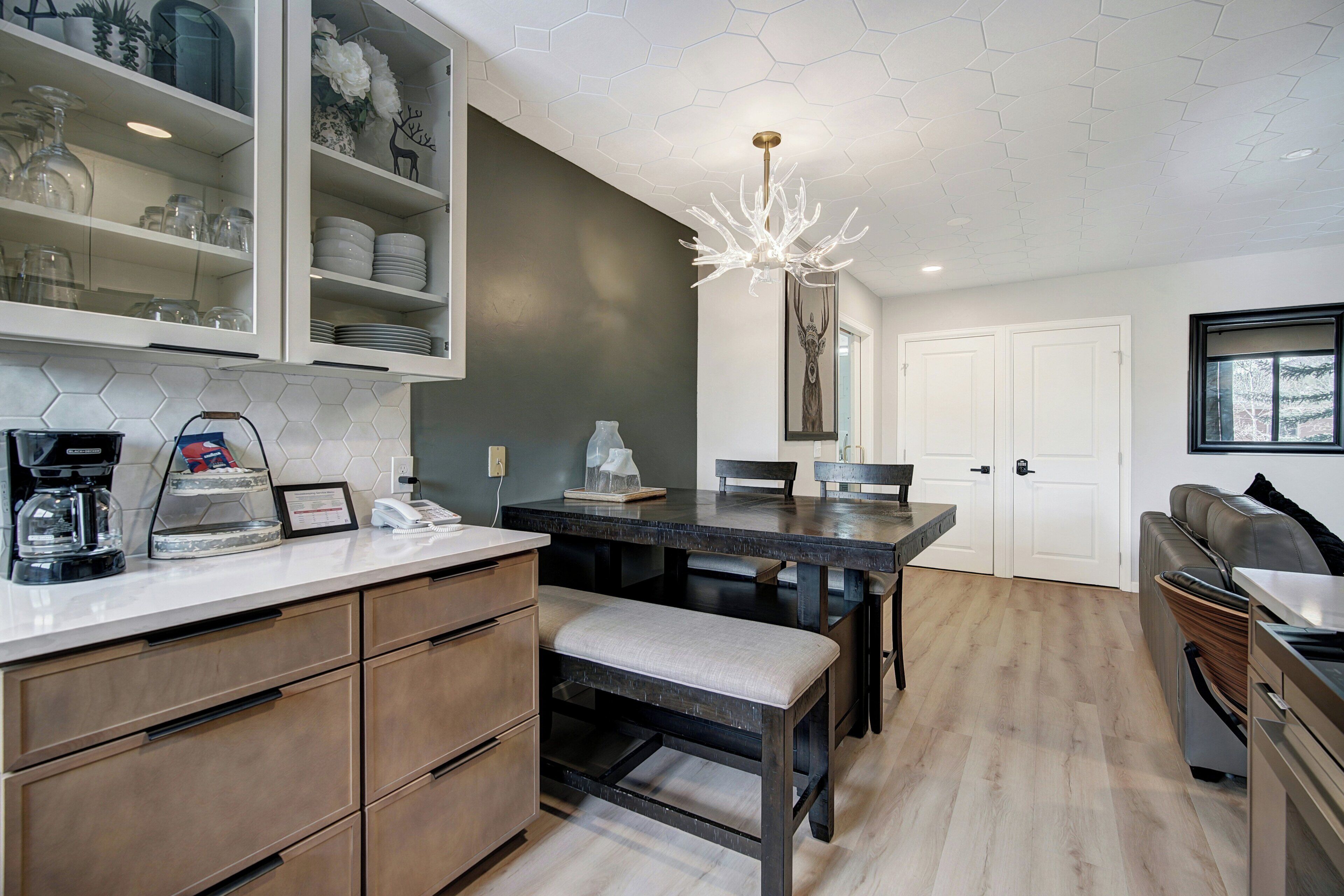 A modern kitchen with a dining area, a bench, and a coffee maker.