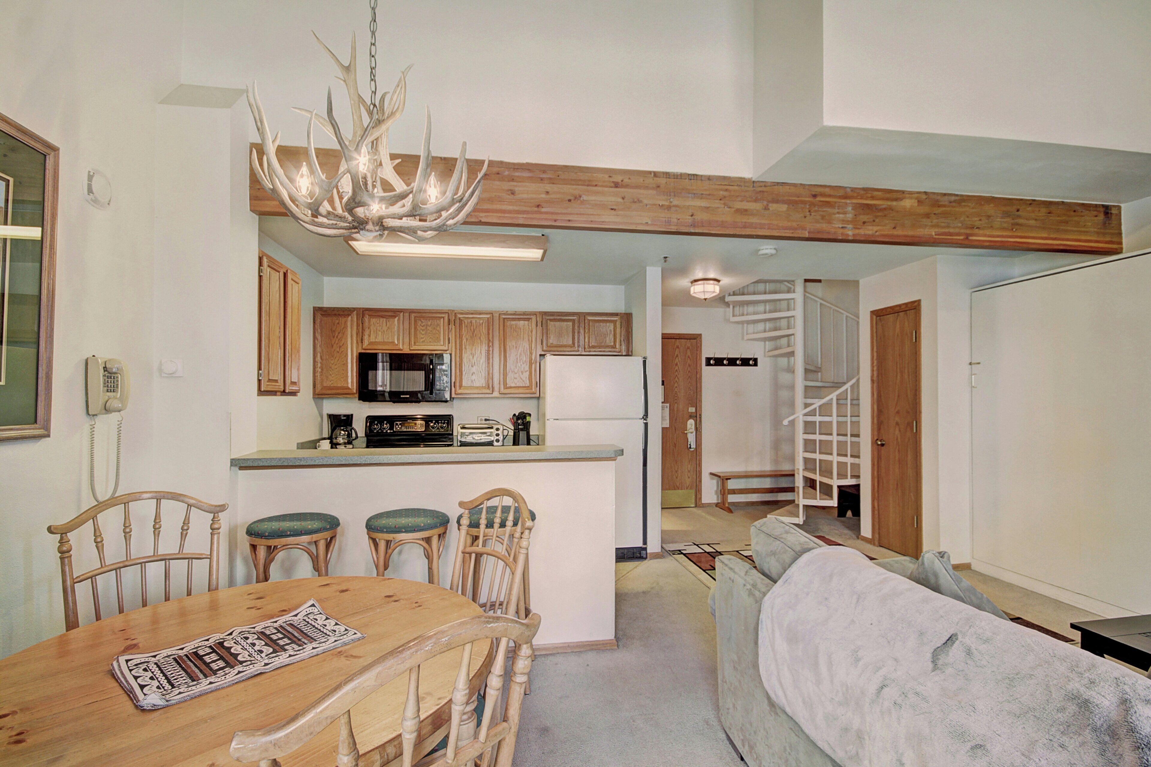 A spacious kitchen with wooden cabinets, a central island, and a chandelier.