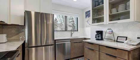 A modern kitchen with stainless steel appliances, a dishwasher, and a coffee maker.