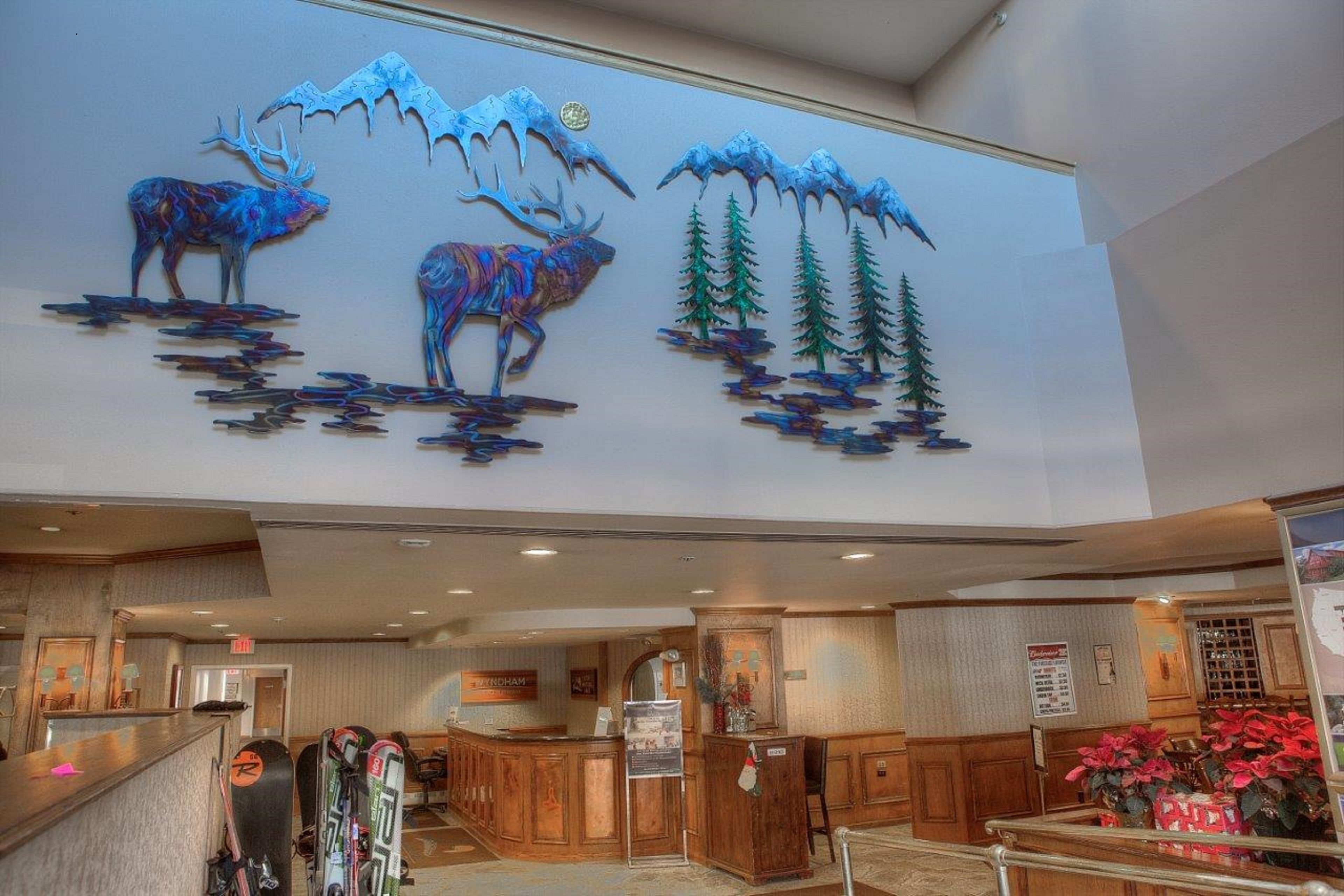 Una hall d'albergo con una reception, un grande murale raffigurante fauna selvatica e attrezzatura da sci.