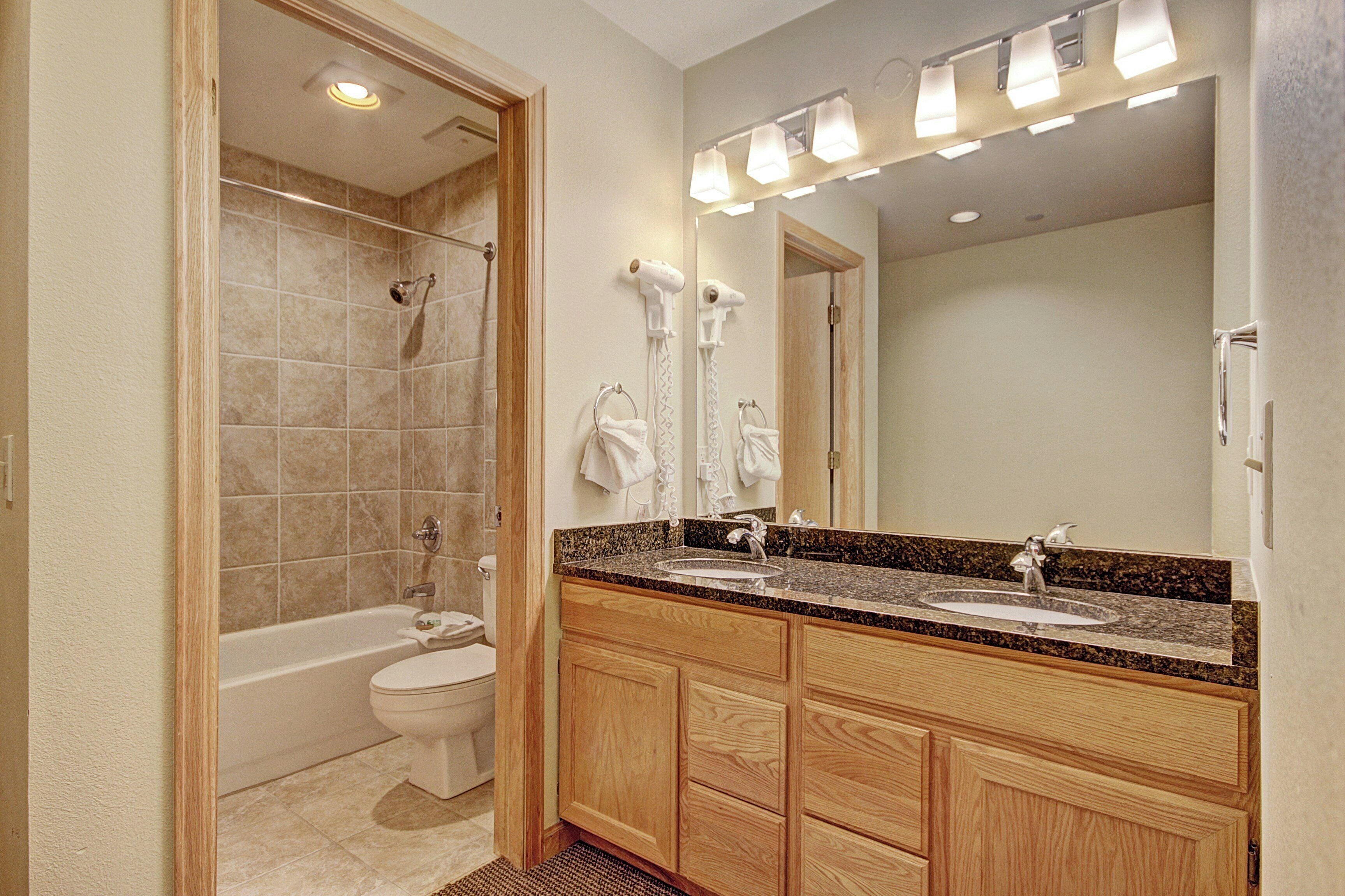 A modern bathroom with a bathtub, a double sink vanity, and a large mirror.