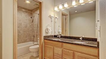A modern bathroom with a bathtub, a double sink vanity, and a large mirror.