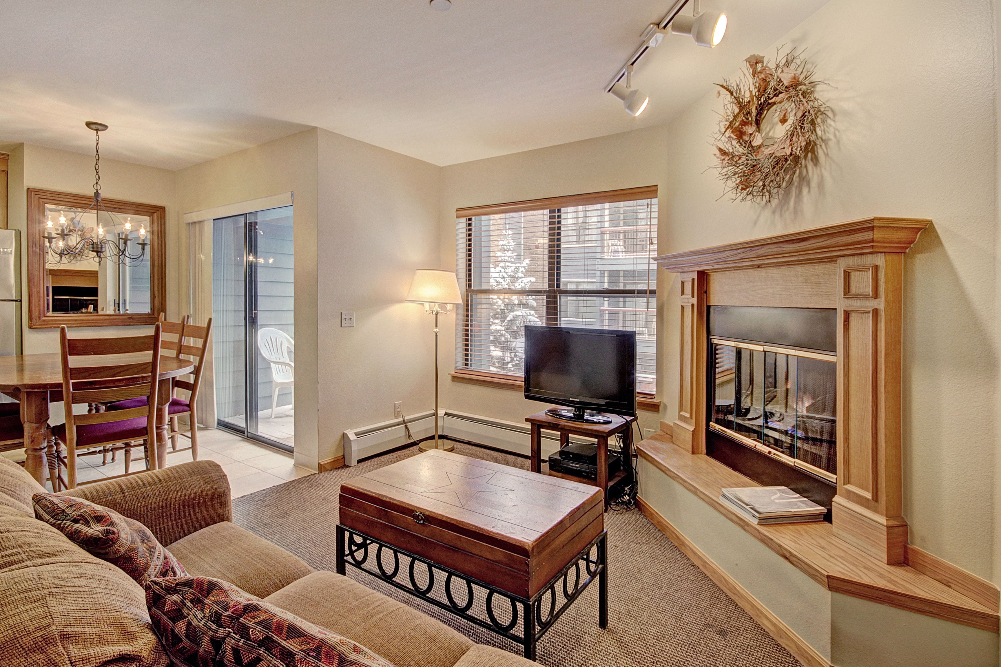 A living room with a fireplace, television, and a dining area with chairs and a table.