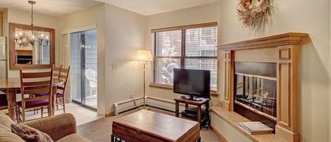 A living room with a fireplace, television, and a dining area with chairs and a table.