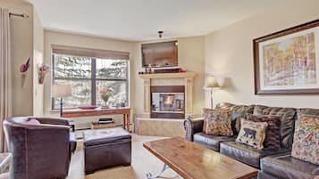 A living room with a fireplace, leather furniture, and a television.