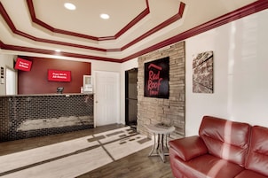 Un hall d'hôtel avec un comptoir d'accueil, une enseigne Red Roof Inn, un canapé en cuir et une cheminée.
