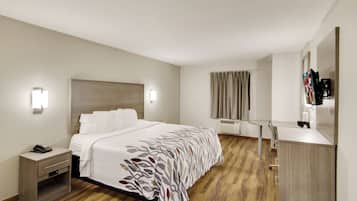 Ein Hotelzimmer mit Bett, Nachttisch, Lampe und Spiegel.
