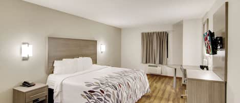 A hotel room with a bed, bedside table, lamp, and a mirror.