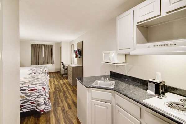 Una habitación de hotel con cama, escritorio, kitchenette y baño.
