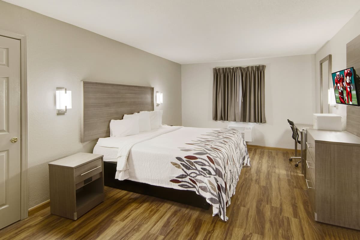 Una habitación de hotel con cama, mesita de noche y armario.