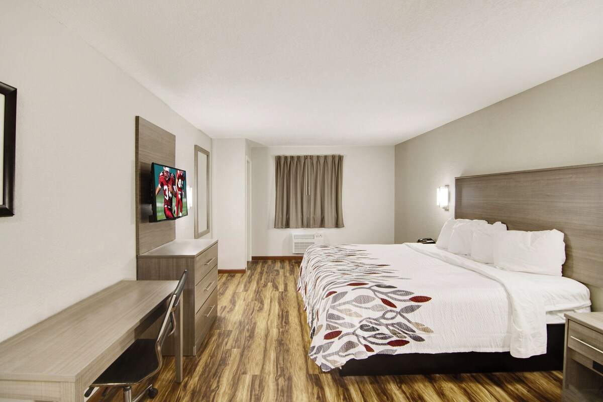 Une chambre d’hôtel équipée d’un lit, d’une table de chevet, d’une télévision et d ’un bureau avec une chaise.
