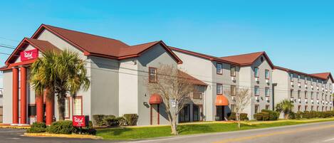 A hotel with a red roof, multiple windows, and a clear sky.