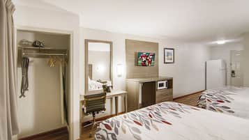 Una habitación de hotel con cama, escritorio con silla, espejo, televisión y armario.