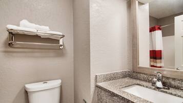 A bathroom with a toilet, a towel rack, a sink, and a mirror.
