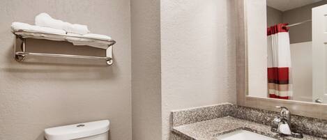 A bathroom with a toilet, a towel rack, a sink, and a mirror.