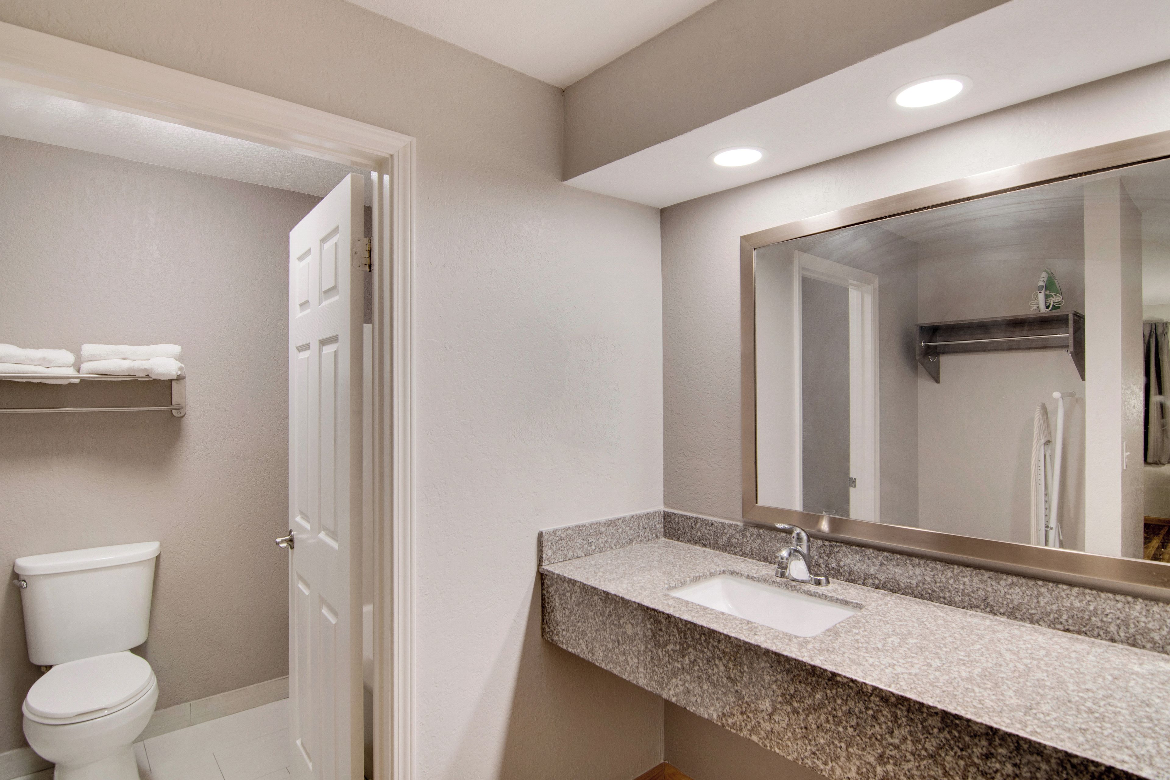 A bathroom with a toilet, sink, and mirror.