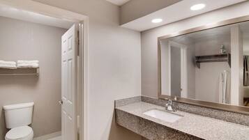 A bathroom with a toilet, sink, and mirror.
