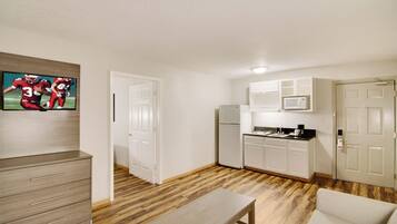 A compact living space with a kitchenette, a dining area, and a television mounted on the wall.