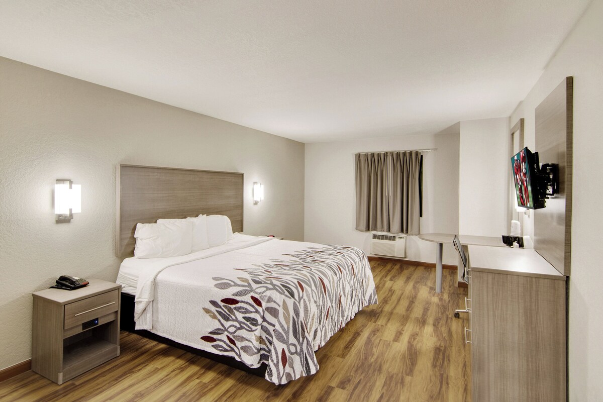 Une chambre d’hôtel avec un lit, une table de chevet, une lampe et un miroir.