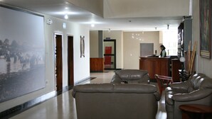 A spacious living area with a large sofa, a dining table, and a kitchen in the background. - Hotel Olimpico Quevedo (Quevedo)