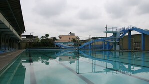 A swimming pool with a blue and white structure, clear water, and a reflection of the sky and buildings. - Hotel Olimpico Quevedo (Quevedo)