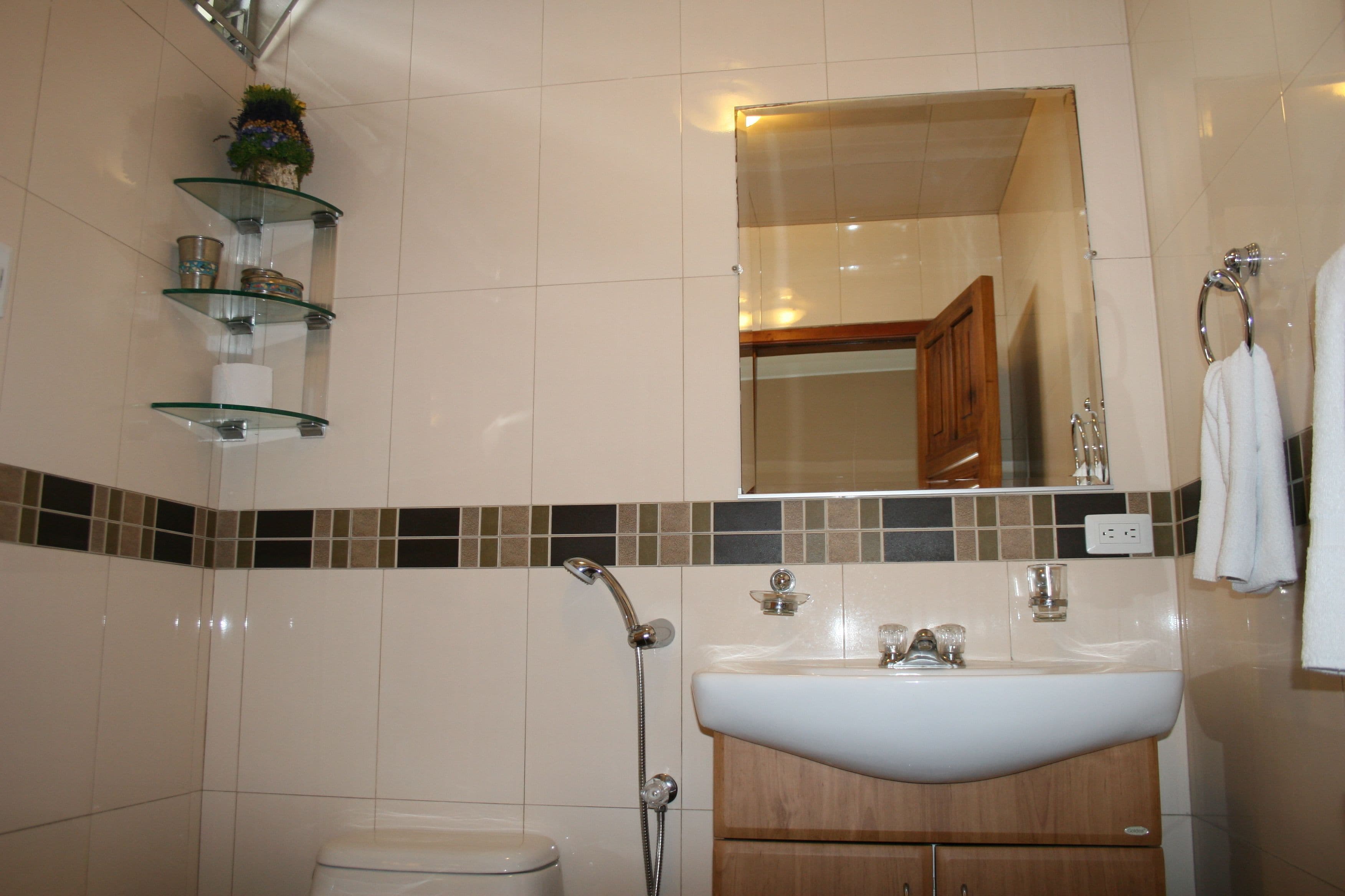 Une salle de bain avec un lavabo blanc, une cabine de douche en verre et des toilettes.