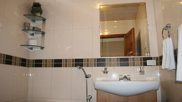 Une salle de bain avec un lavabo blanc, une cabine de douche en verre et des toilettes.