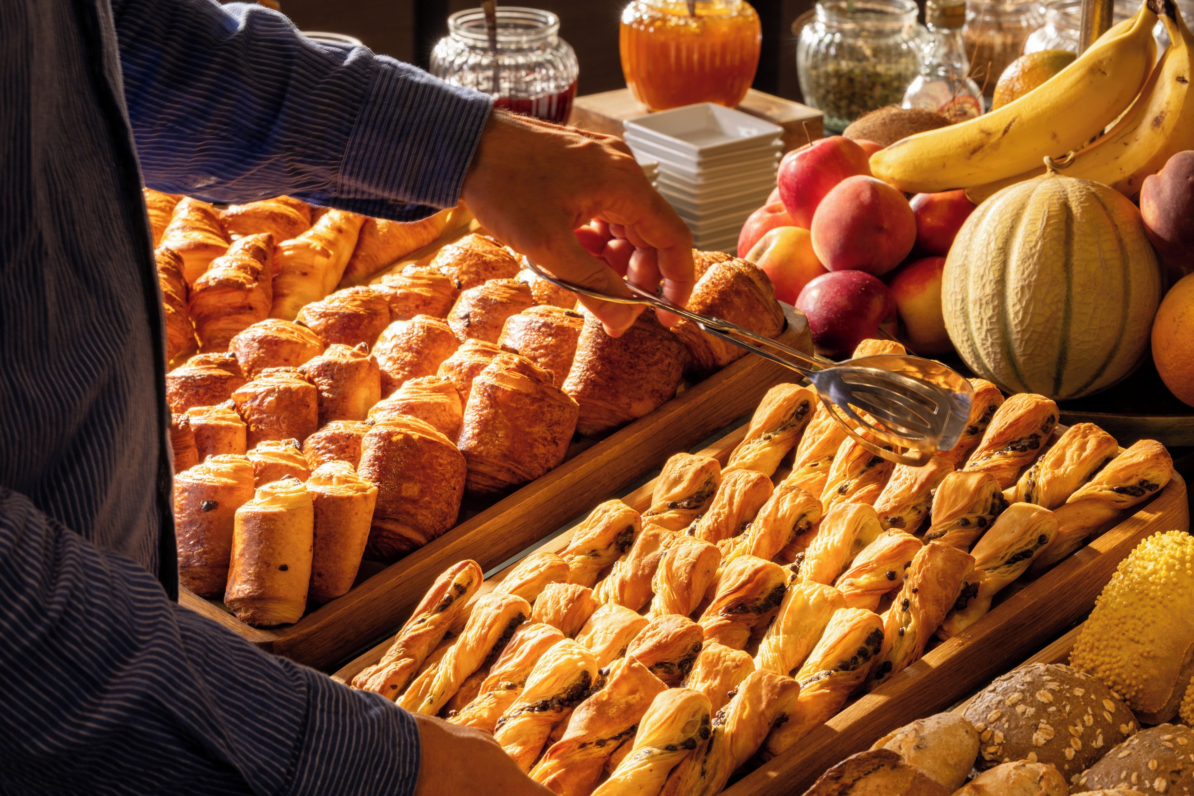 A buffet with various baked goods and fruits.