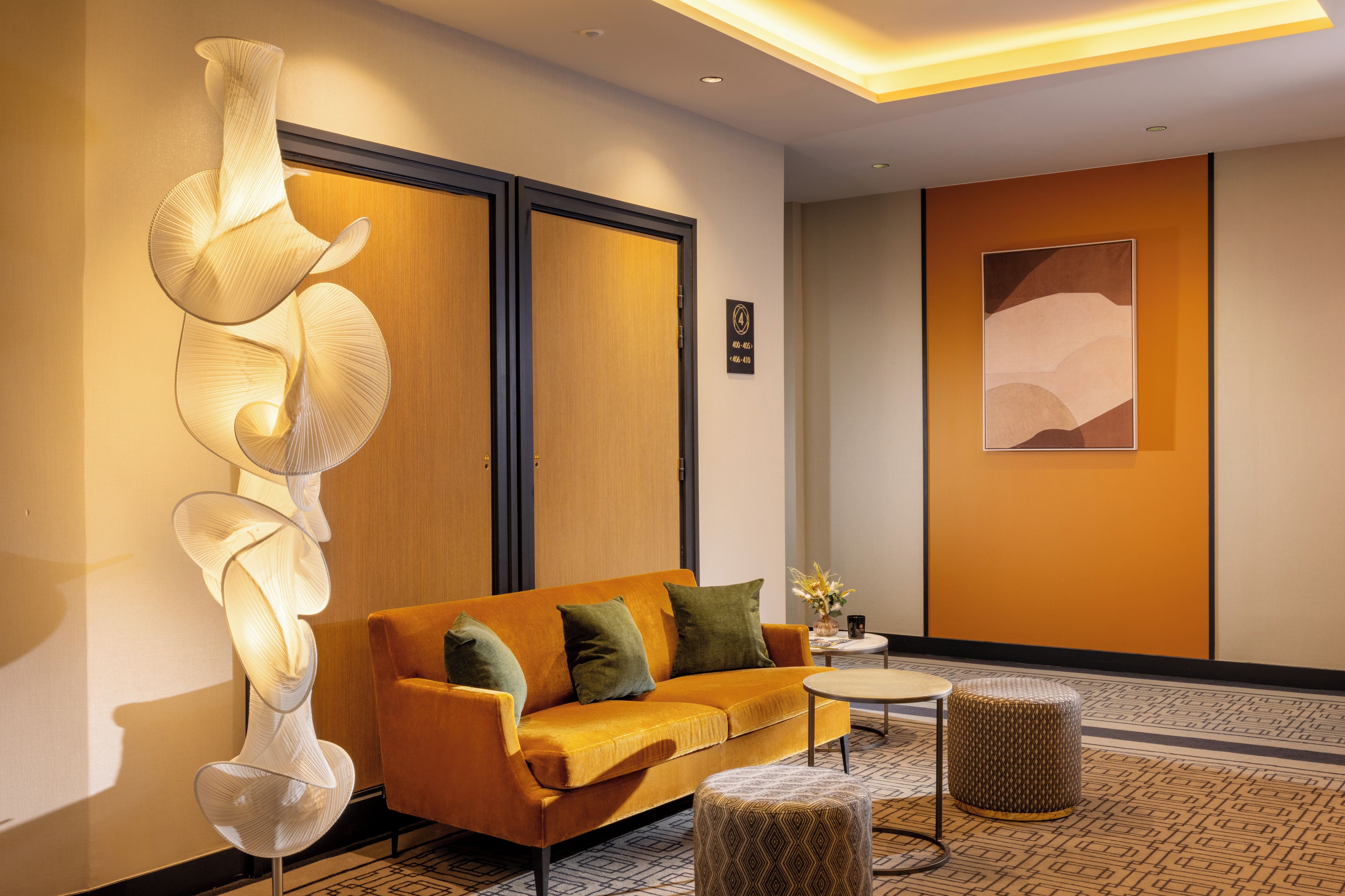 A hotel lobby with a sofa, ottoman, and abstract wall art.