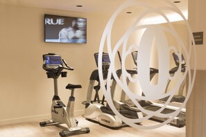 Une salle de remise en forme équipée de tapis de course et d’un vélo d’appartement, d’un écran de télévision et d’un panneau indiquant la présence d’un sauna.