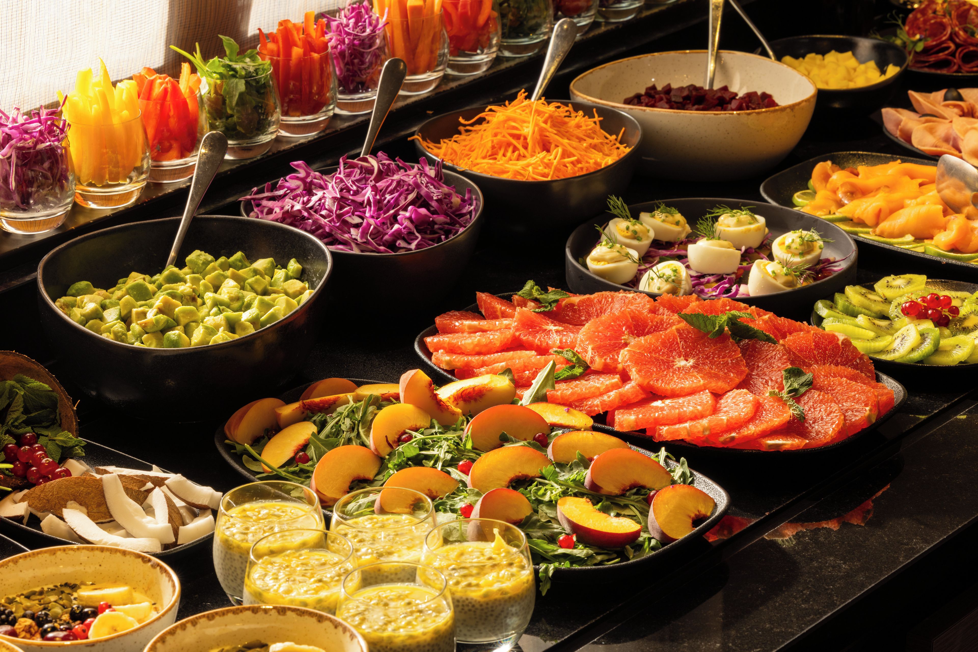 Buffet amb diferents plats, incloent fruita, verdura i aliments preparats.