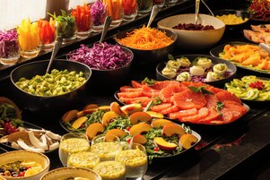 A buffet with various food items including fruits, vegetables, and prepared dishes.