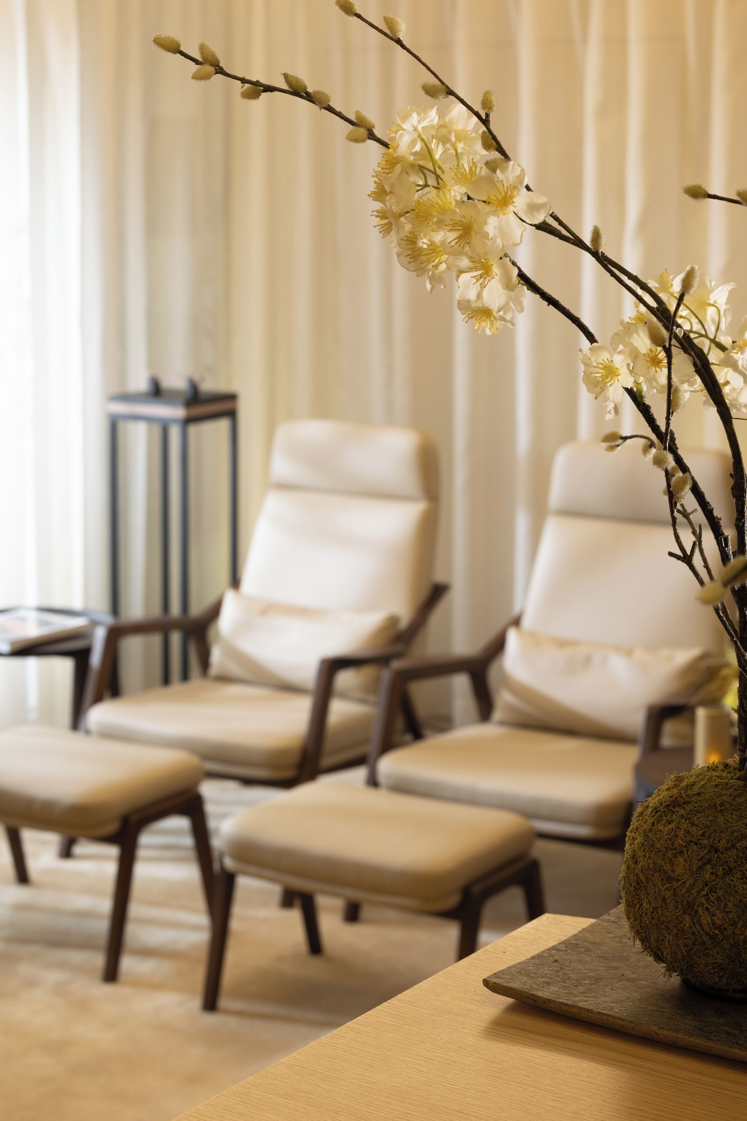 A seating area with two chairs and a bench, a vase with flowers, and a side table.