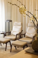 A seating area with two chairs and a bench, a vase with flowers, and a side table.